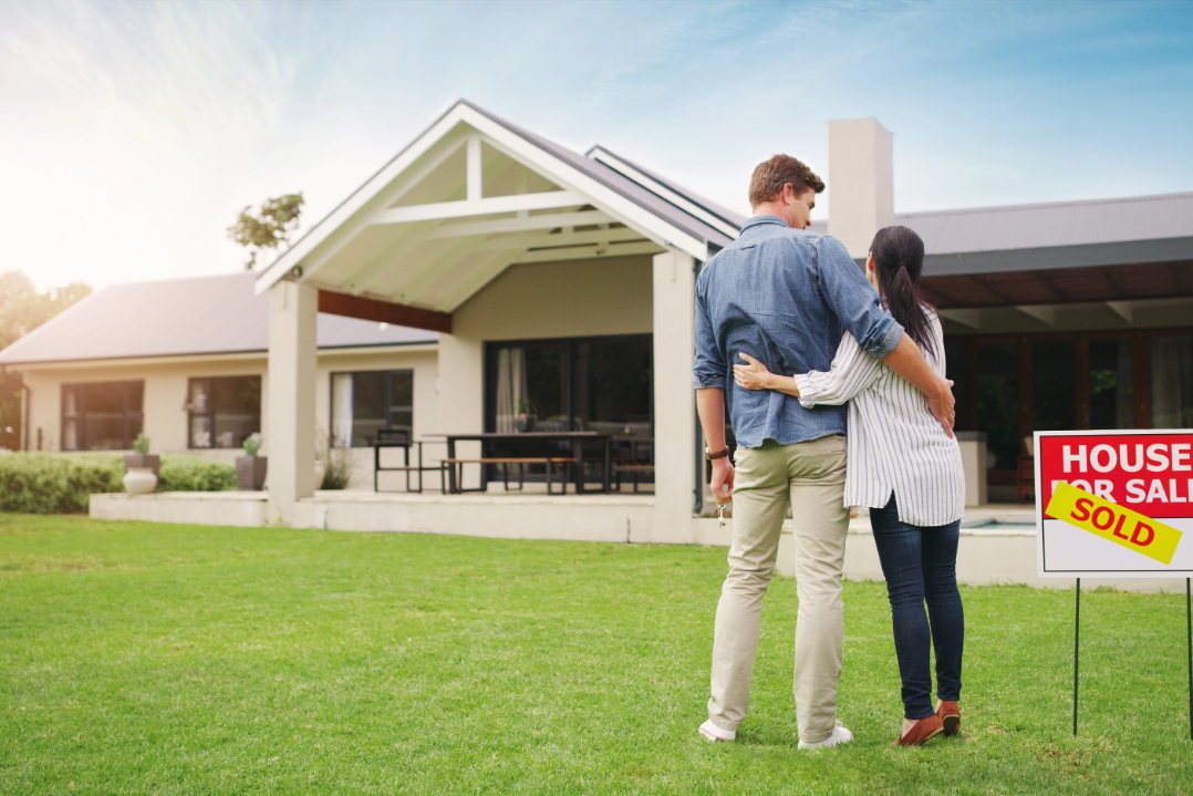 Shot of a young couple admiring their newly purchased house.